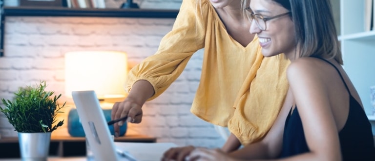 Twee collegas nemen samen de cijfers door op een laptop